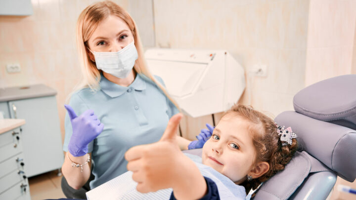 Маленькая девочка в кресле у женщины стоматолога