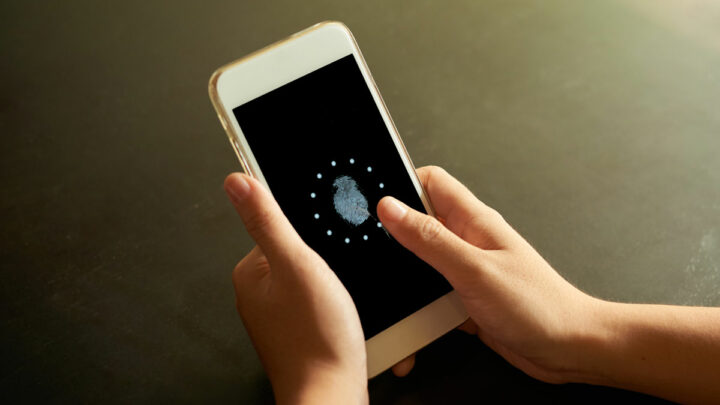 человек держит телефон в руке на котором изображен отпечаток пальца