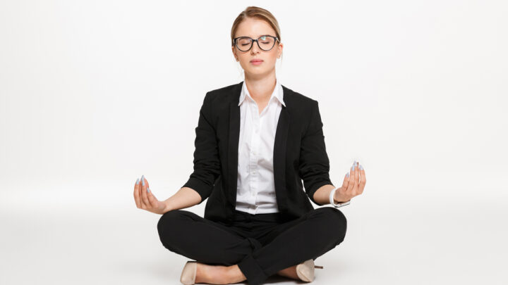 Спокойная блондинка деловая женщина в очках медитации в студии с закрытыми глазами