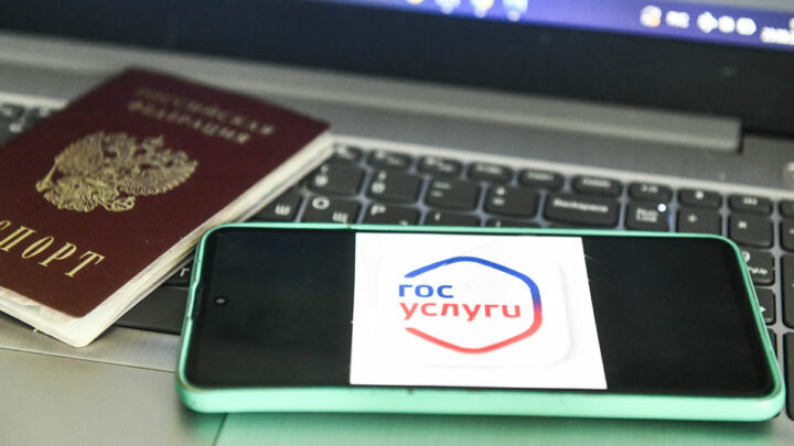 Паспорт лежит на клавиатуре ноутбука, рядом телефон на экране логотип Госулуги