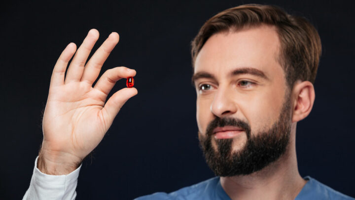 Мужчина держит в руках красную таблетку