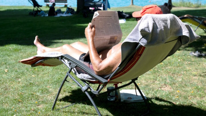 Мужчина читает газету в шезлонге