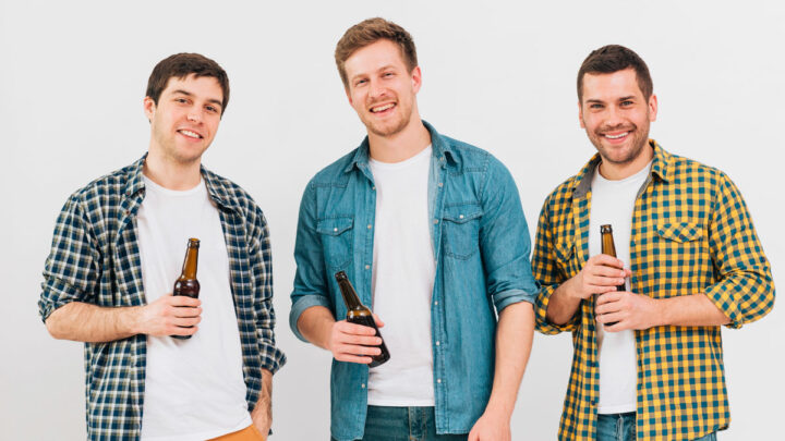 Трое мужчин стоят с бутылками в руках, улыбаются