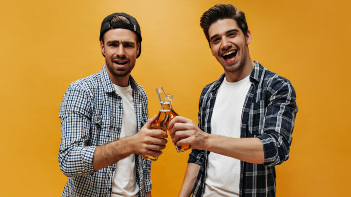 Двое молодых людей чокаются бутылками