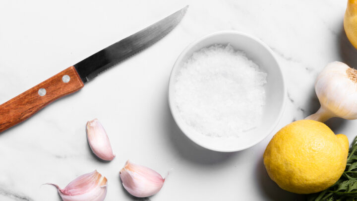 Ножь, соль, чеснок и лимон лежат на столе