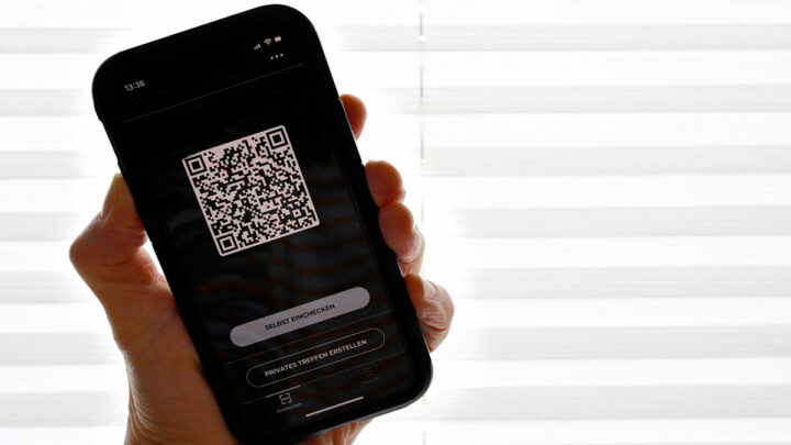 Рука держит телефон, на телефоне изображен QR-код