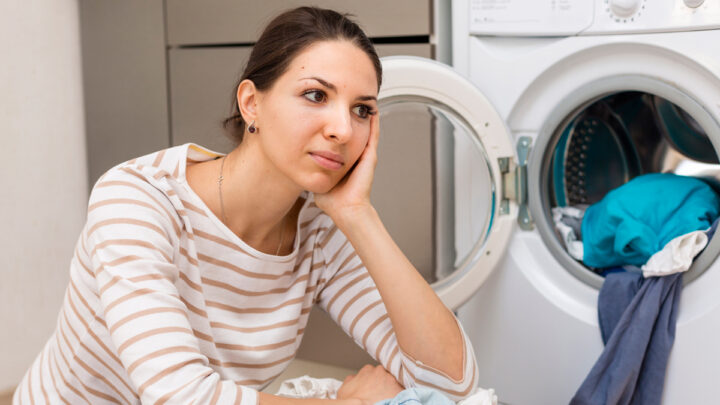 Женщина сидит около стиральной машинки