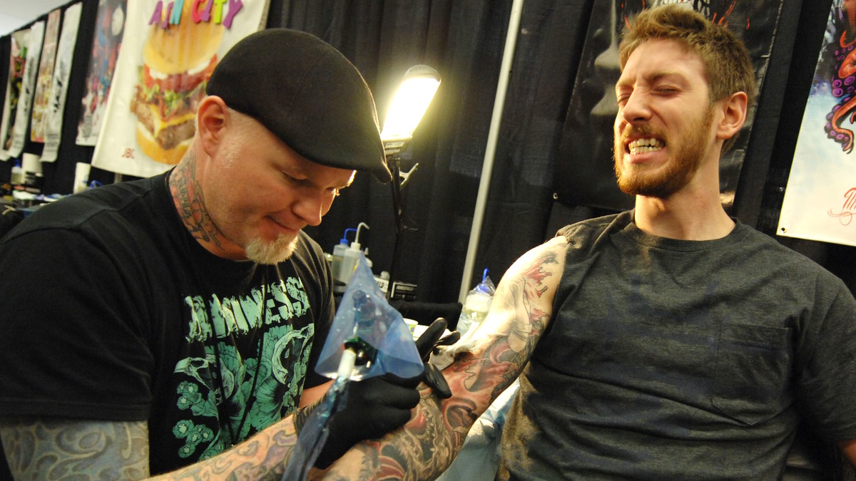 Мастер делает татуировку клиенту
