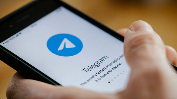 Смартфон в руках, на экране открывается приложение Telegram