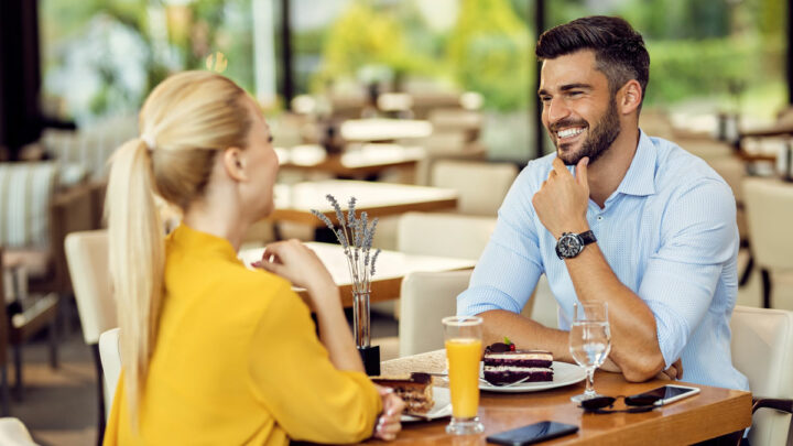 Молодая девушка сидит в ресторане за столом с улыбающимся мужчиной