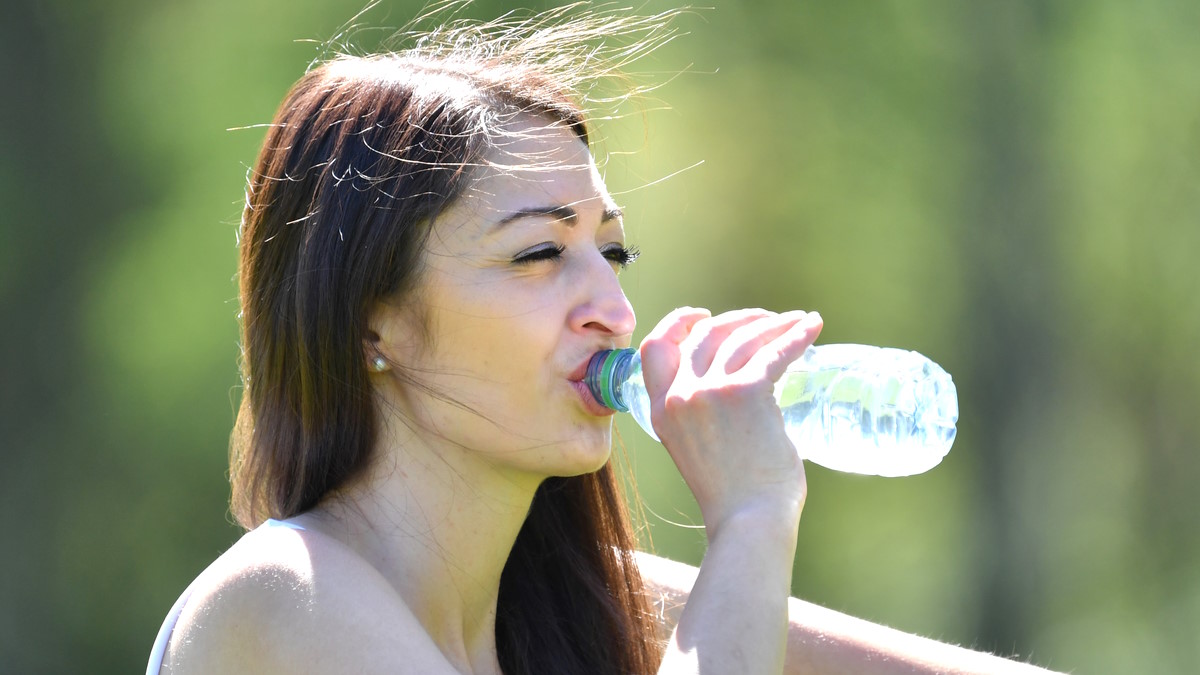 Женщина пьет из пластиковой бутылки