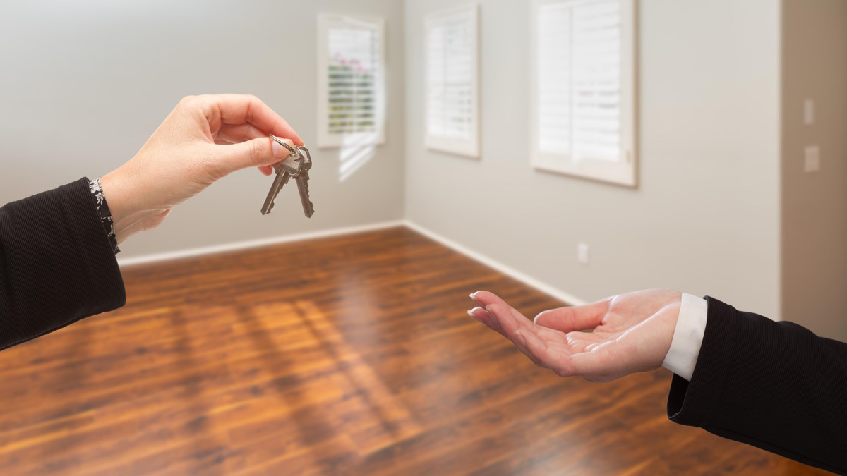 Женщина передает ключи от квартиры покупателю