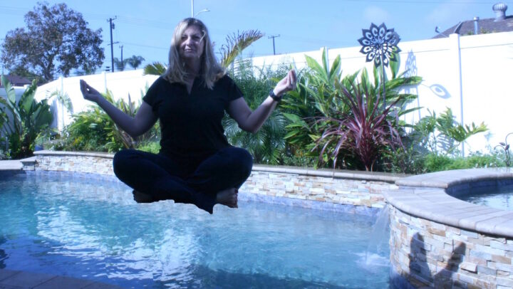 Женщина в позе лотоса над бассейном