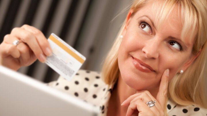 Женщина задумчиво держит банковскую карту