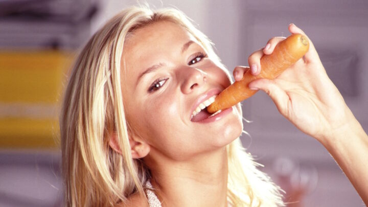 Девушка ест морковь