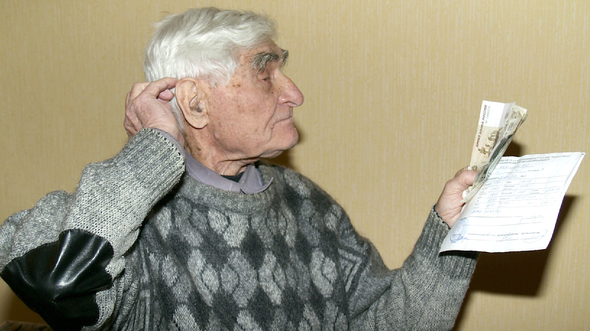 Пожилой мужчина держит квитанции ЖКХ