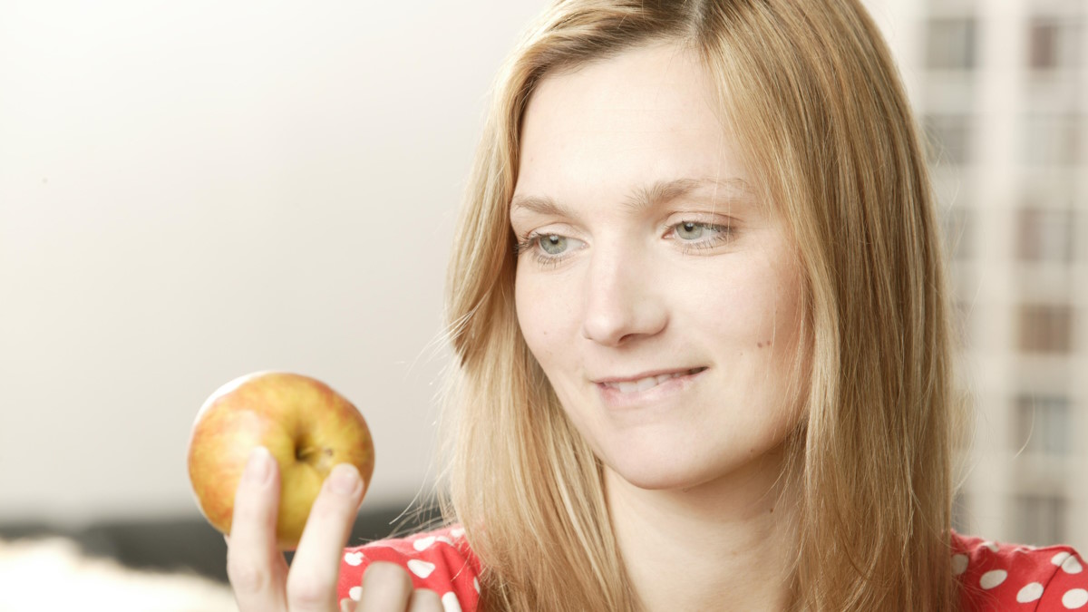 Женщина смотрит на яблоко в руке