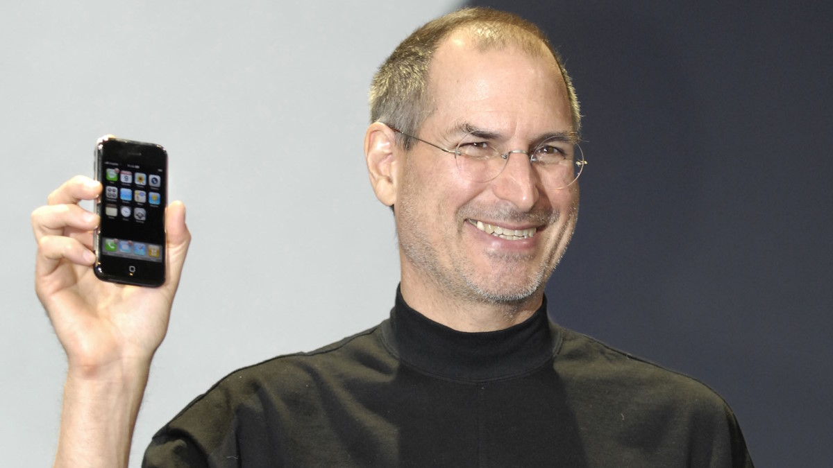 Стив Джобс держит в руке Айфон