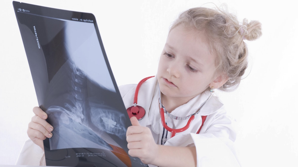 Девочка в медицинском халате рассматривает рентгеновский снимок