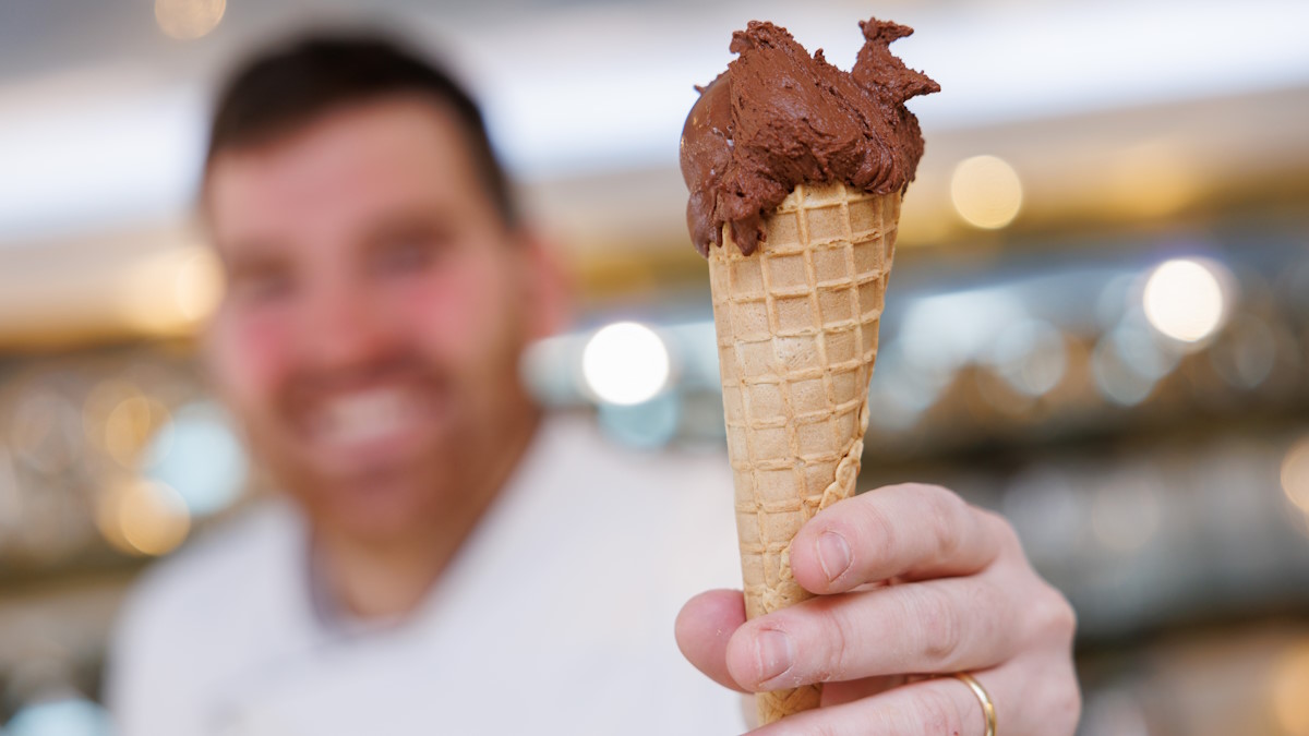 Мужчина протягивает перед собой рожок шоколадного мороженого