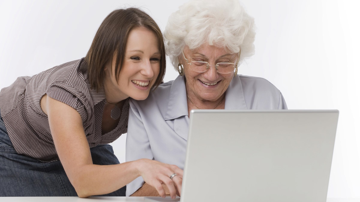 Молодая девушка помогает пожилой с ноутбуком