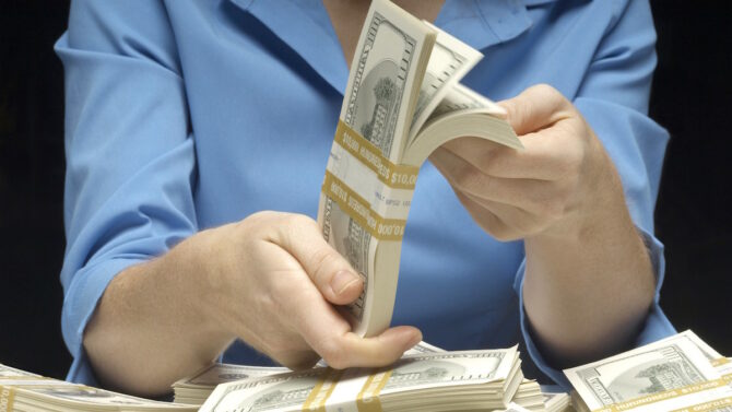 Женщина держит в рукам пачку долларовых банкнот