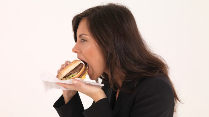 Женщина ест гамбургер