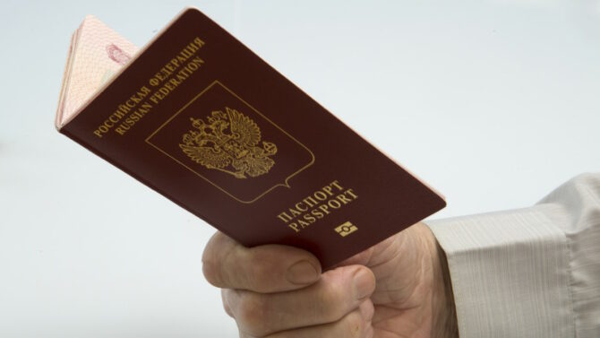 Мужская рука держит Российский паспорт