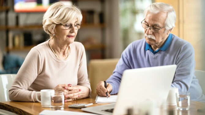 Пенсионеры сидят за столом с ноутбуком