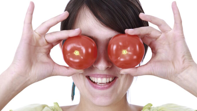 Женщина держит помидоры на глазах