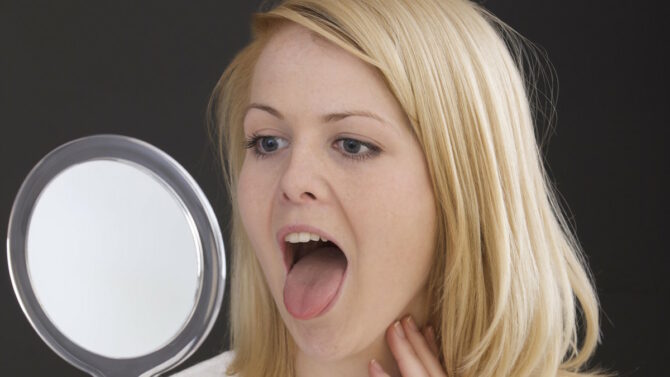 Женщина рассматривает в зеркале свой язык