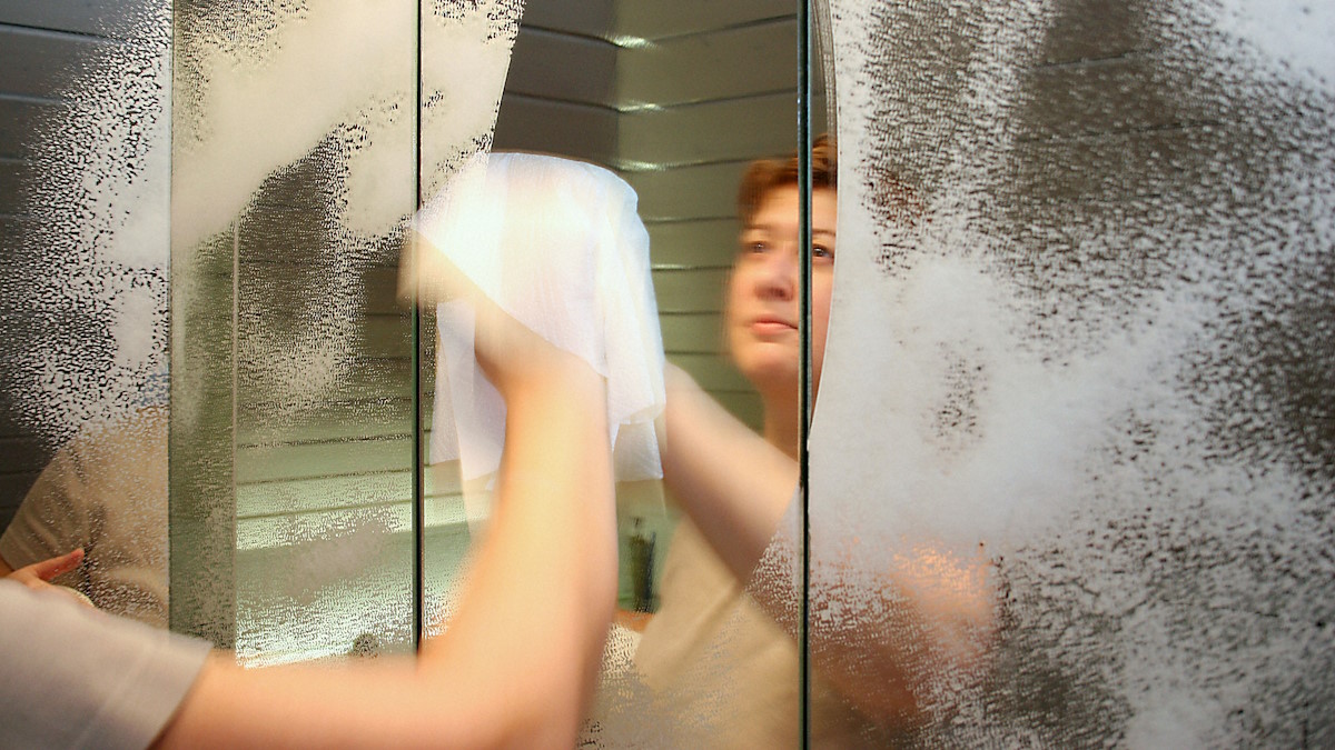 Женщина моет зеркало