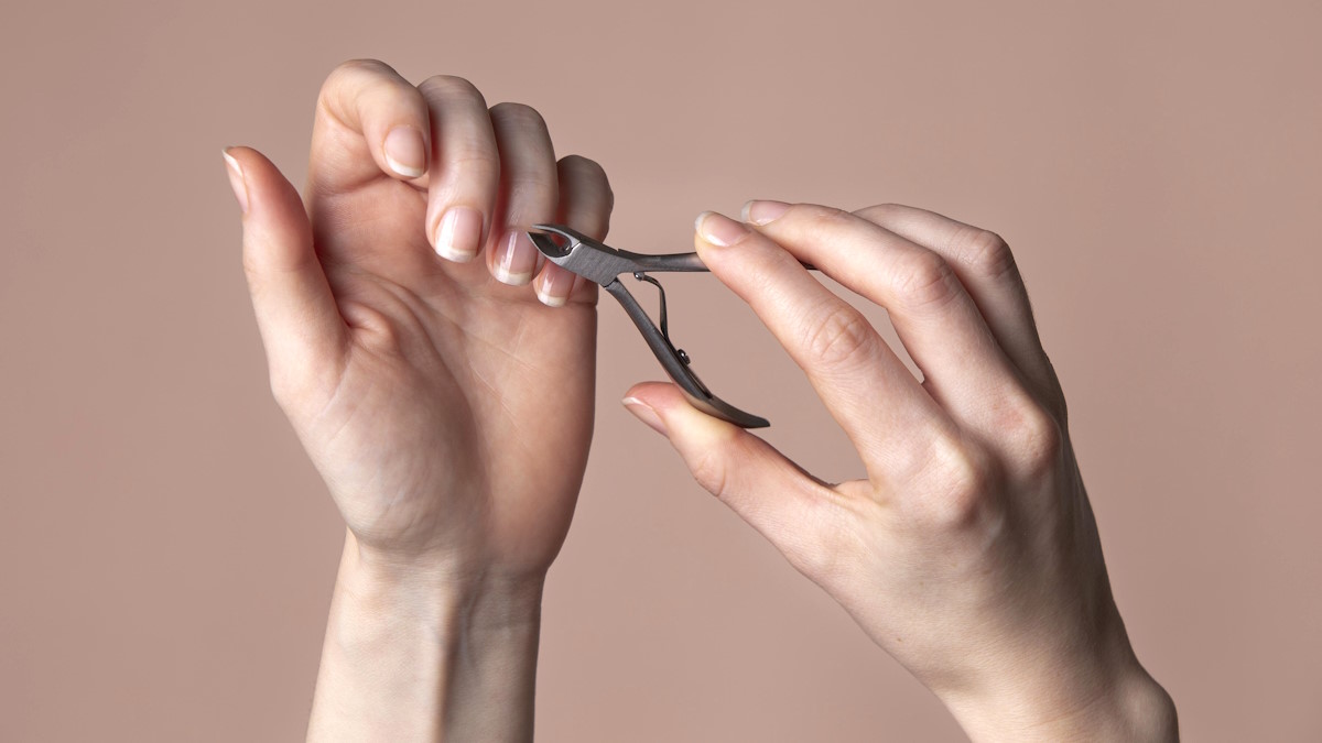 Женщина обрезает кожу у ногтей