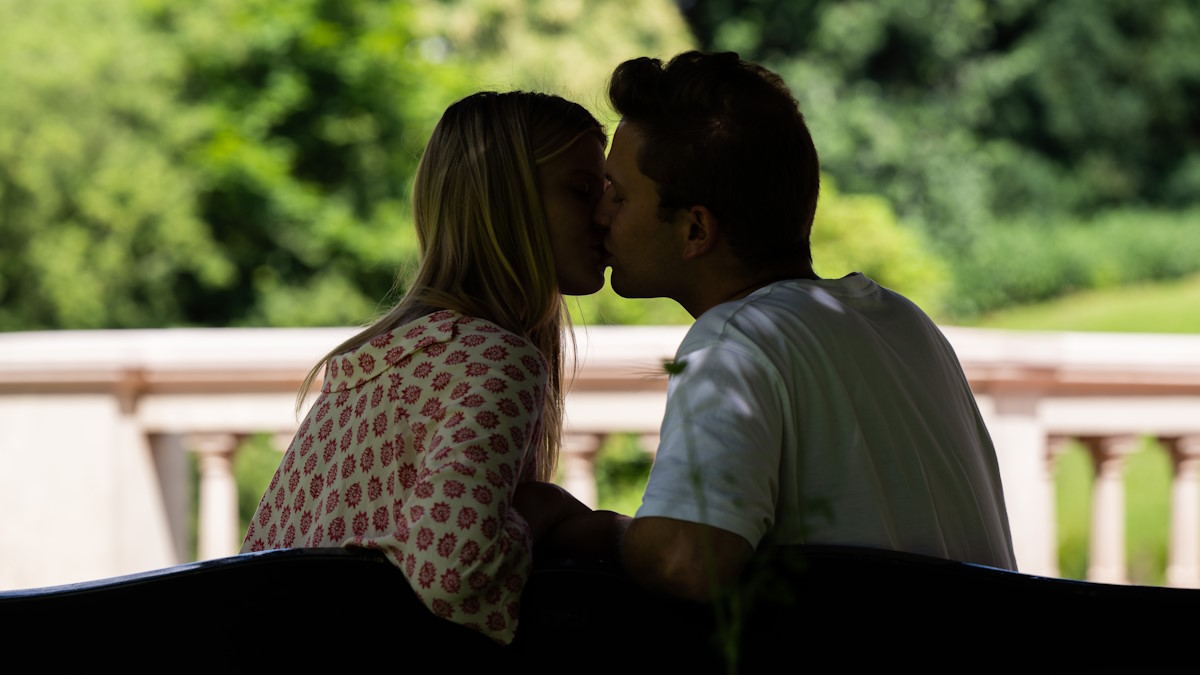 Мужчина и женщина целуются на скамейке в парке