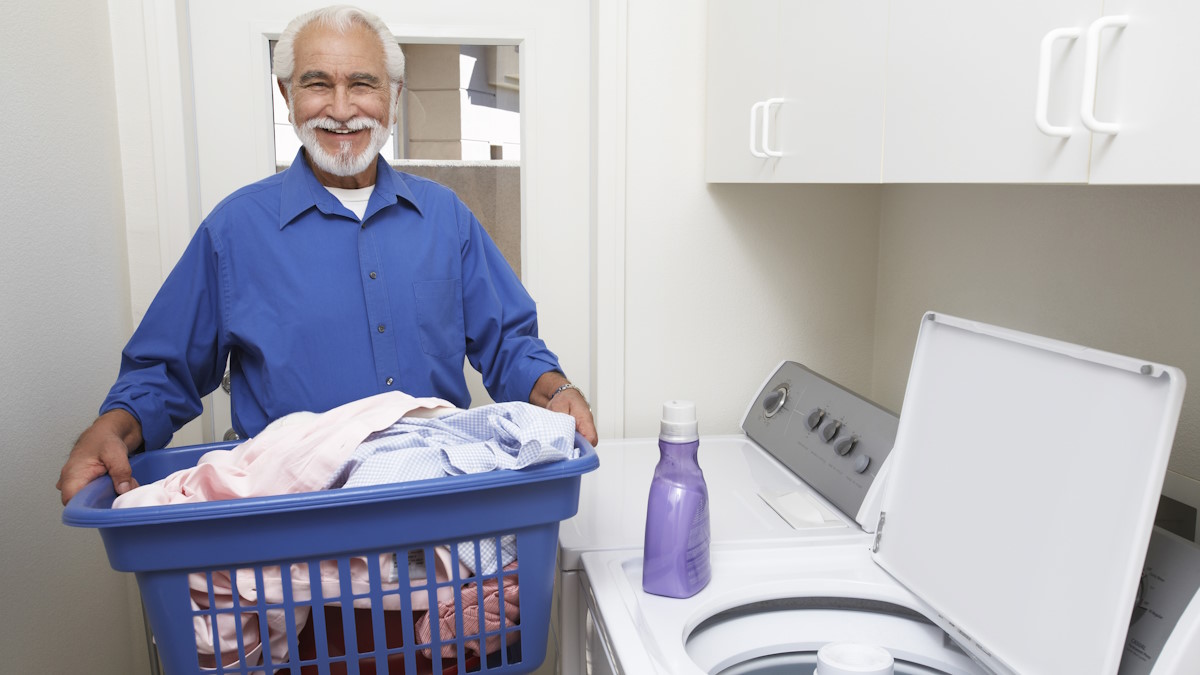 Мужчина с корзиной белья возле стиральной машины