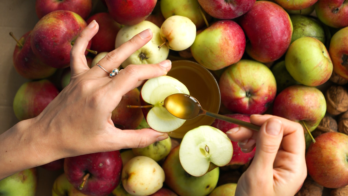 Женщина наливает мед на яблоко