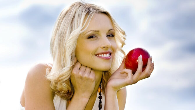 Женщина держит в руке яблоко